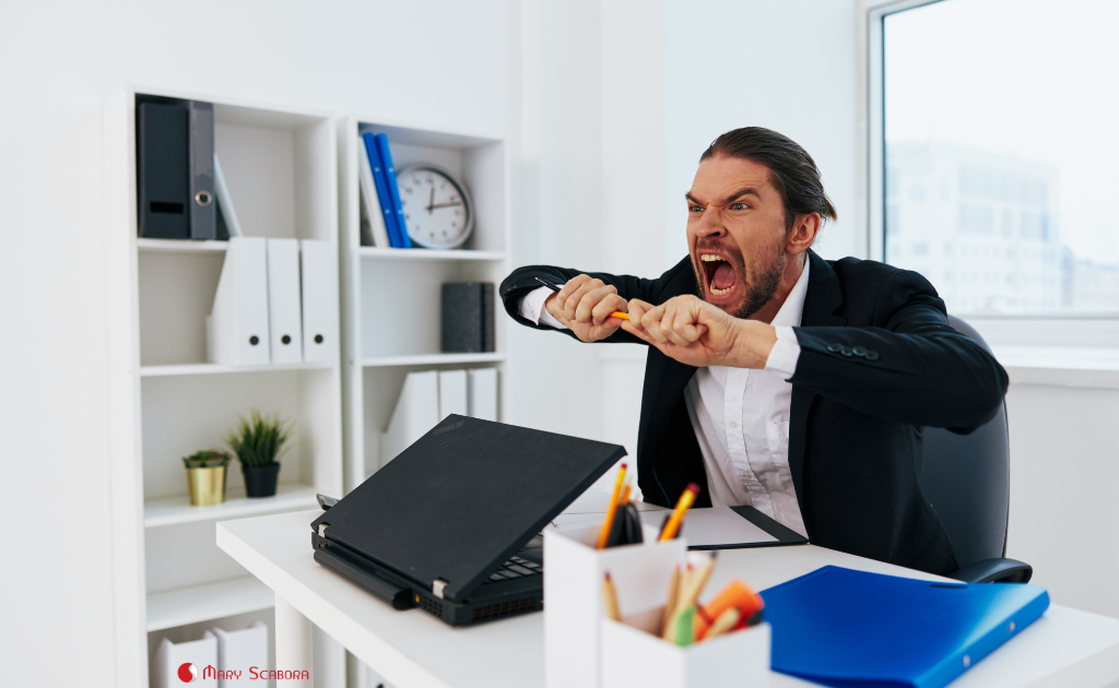 Um homem no trabalho demonstrando raiva ilustra a falta de inteligência emocional: a incapacidade de gerenciar emoções de maneira eficaz em situações de estresse.