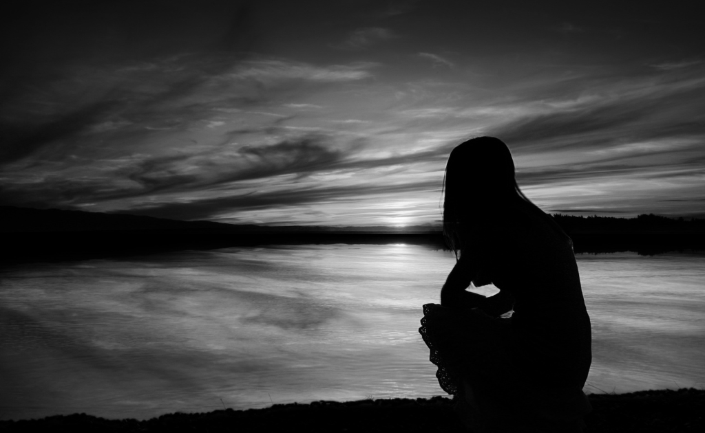mulher observando o por do sol com sintomas da ansiedade e sentimento de solidao