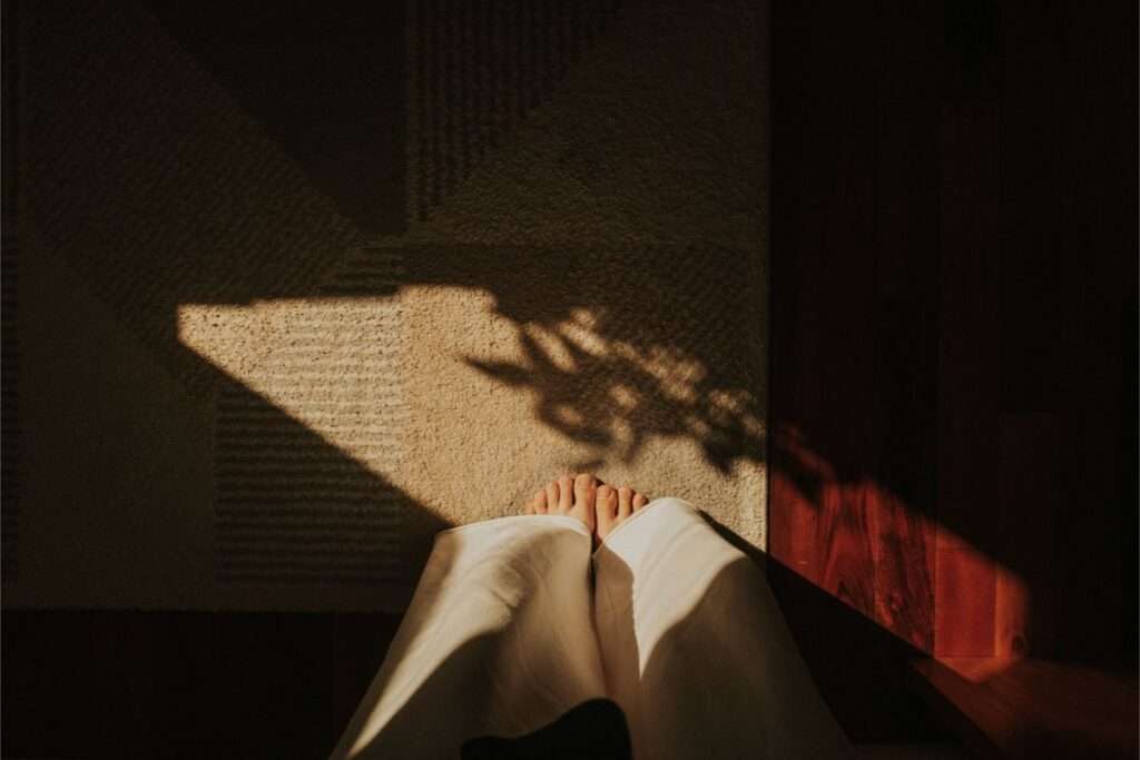 Pessoa sentada no chão próxima a uma faixa de luz