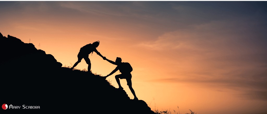 Pessoa ajudando outra a subir uma montanha ao pôr do sol, simbolizando a importância do apoio profissional no tratamento do pânico