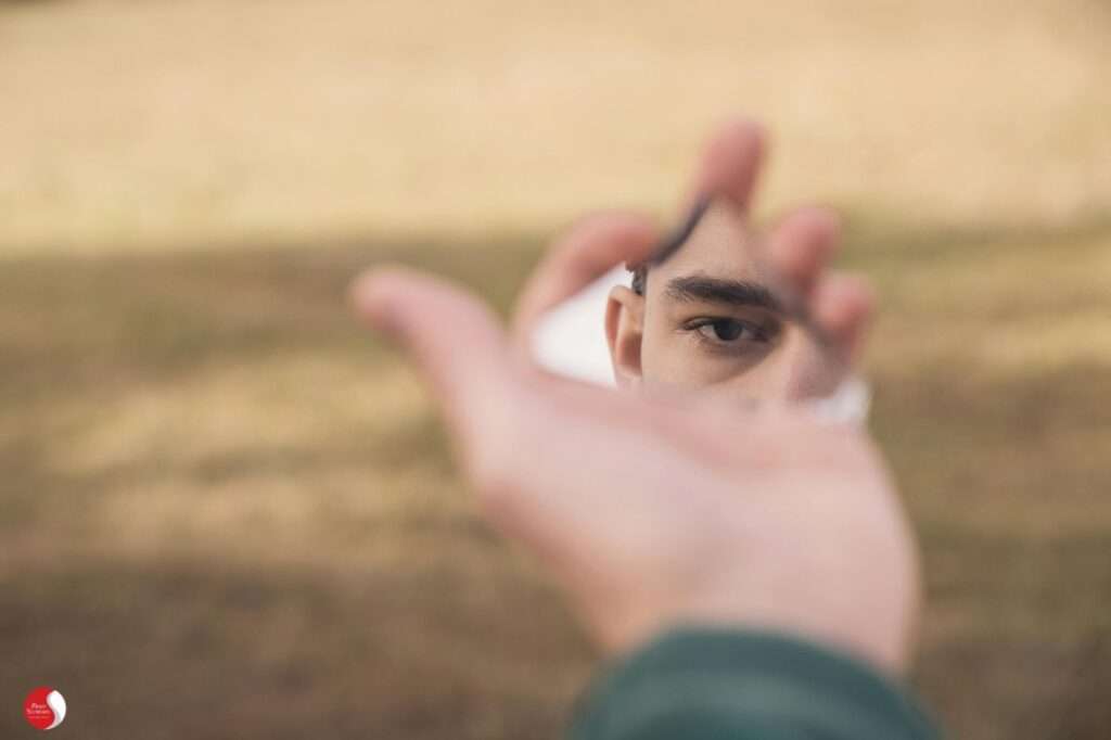 Pessoa diante de espelho quebrado simbolizando a fragmentação da identidade no esgotamento mental.