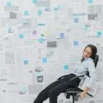 Mulher exausta cercada por relatórios, simbolizando burnout, estresse e a importância do afastamento para recuperação.