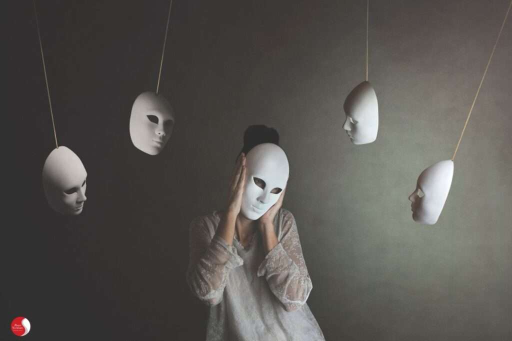 Máscaras penduradas simbolizando a dissociação entre aparência e identidade em profissionais em burnout.
