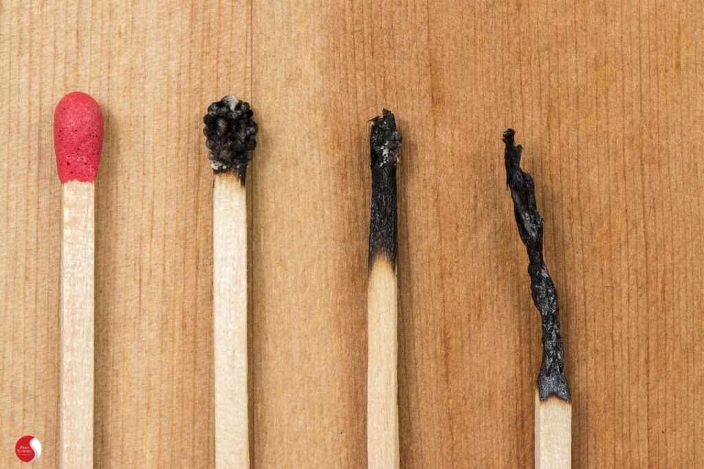 Quatro fósforos lado a lado, cada um em um estágio diferente de queima, simbolizando a progressão do burnout do vigor ao colapso.