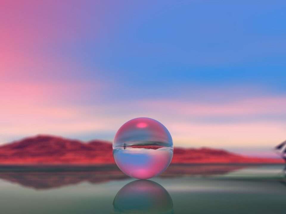 Esfera de vidro refletindo uma paisagem, com montanhas e barco ao fundo.