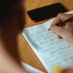 Mulher escrevendo à mão em caderno aberto, representando o processo de elaboração emocional na psicoterapia
