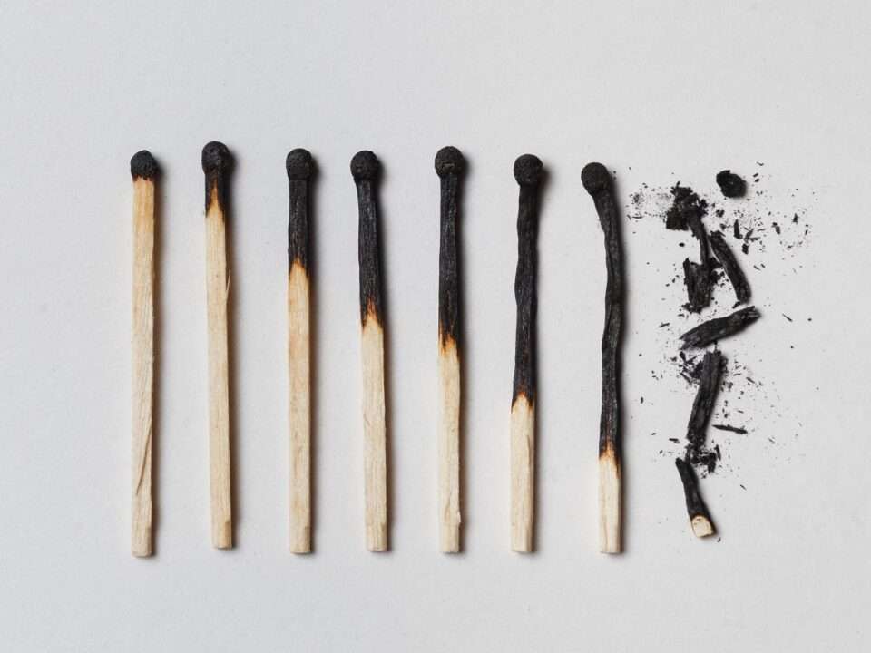 Fósforos queimando progressivamente até se desfazerem em cinzas, representando esgotamento mental, burnout e exaustão emocional causada por hiperfuncionamento contínuo.